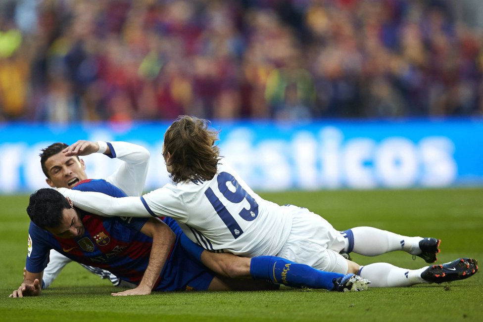 Cristiano Ronaldo y Luka Modric caen al suelo junto a Sergio Busquets.